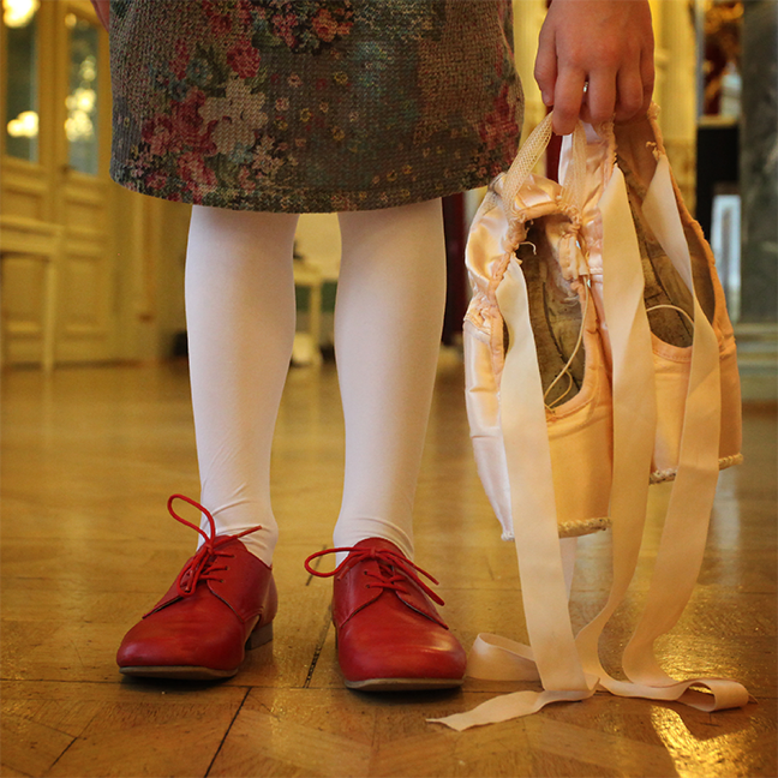 Mädchen mit Spitzenschuhen in der Hand.