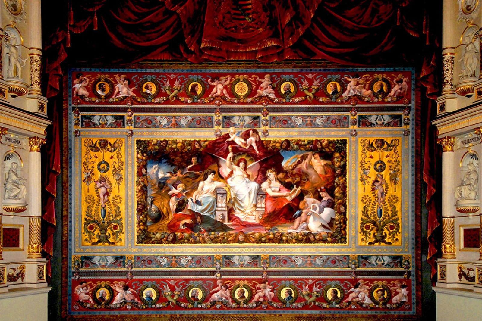 Der reich verzierte Schmuckvorhang der Semperoper mit einer aufwendig gemalten mythologischen Szene, ornamental gerahmt und von tiefroten Vorhängen umgeben.
