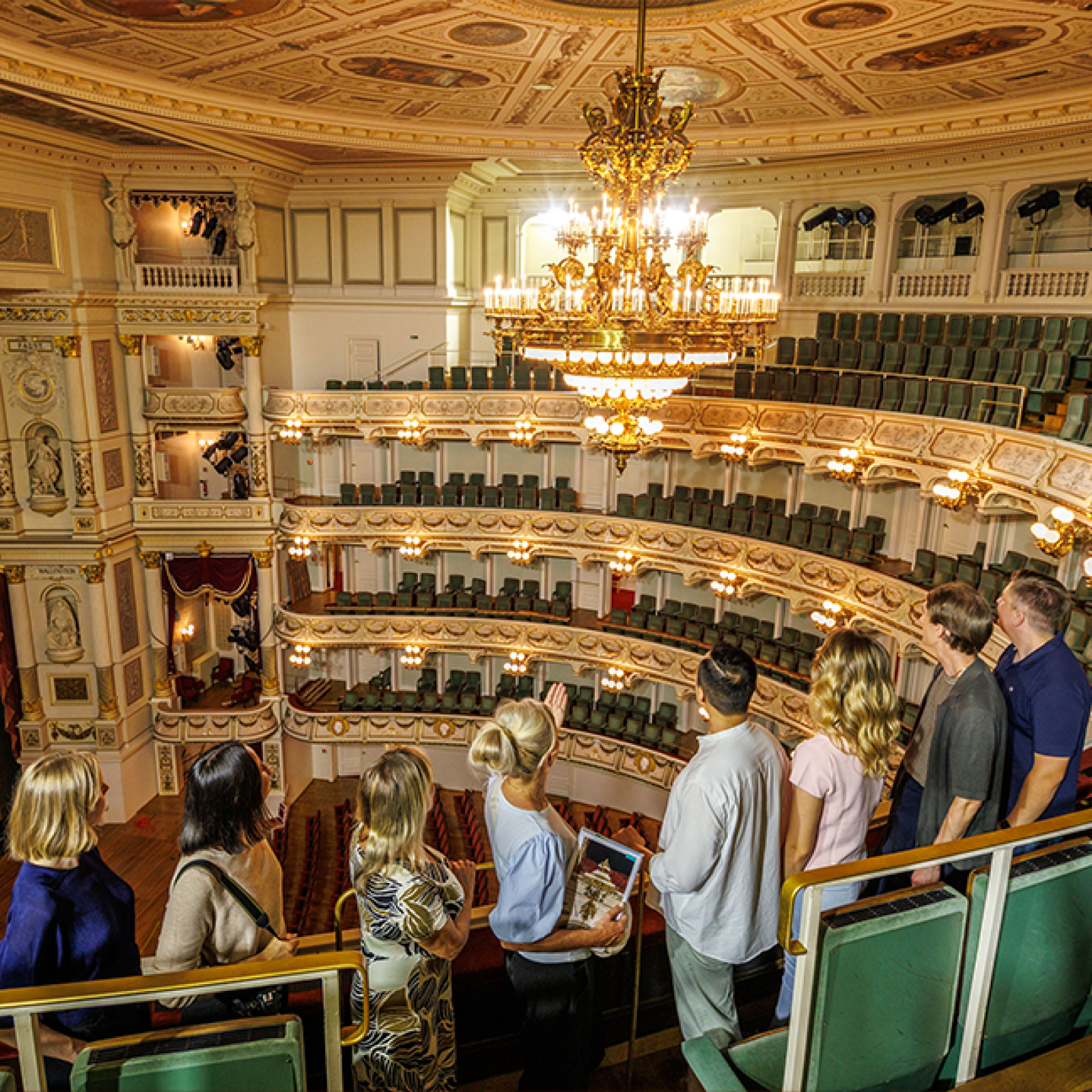 Prächtiges Interieur mit hohen grünen Marmorsäulen, verzierten Bögen, Kronleuchtern und reich dekorierten Decken in einem historischen Opernhaus.