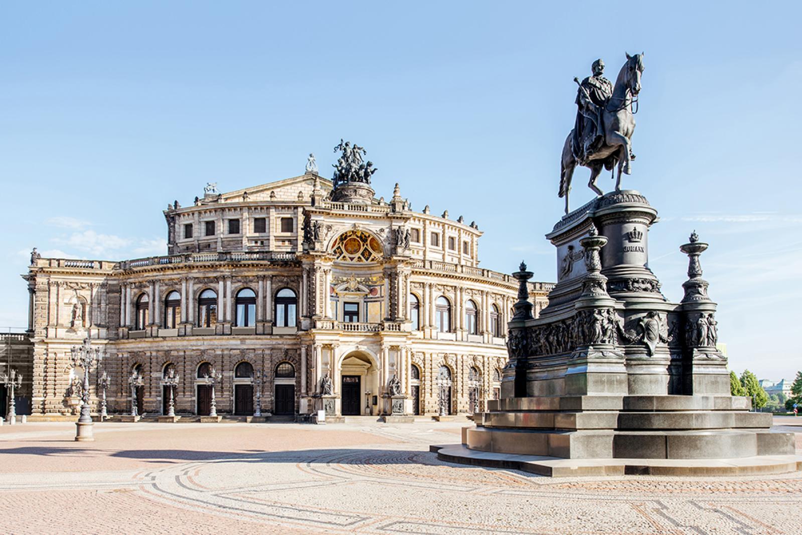 Die Semperoper in Dresden vom Theaterplatz aus gesehen, mit der historischen Fassade des Opernhauses und dem markanten Reiterstandbild im Vordergrund bei klarem Himmel.